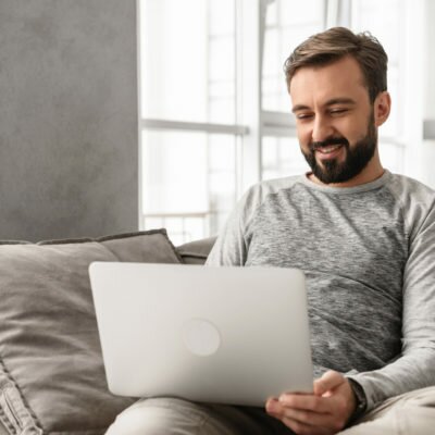 Young man sitting on couch with laptop canstockphoto57679388